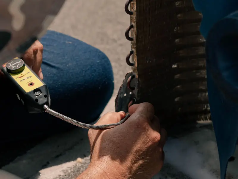 Technician replacing a capacitor in an outdoor AC unit