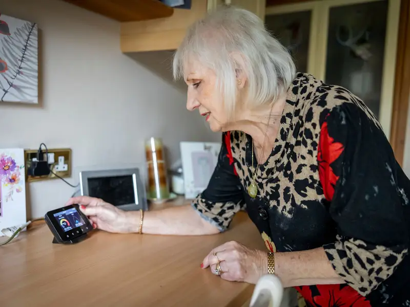Technician helping an older homeowner with her thermostat