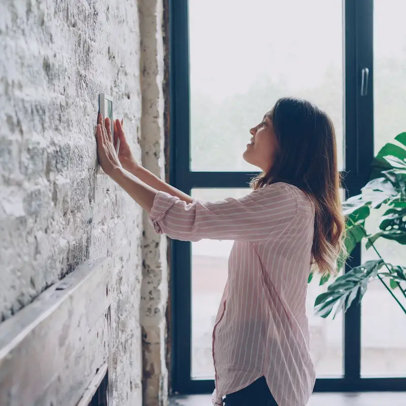 Homeowner adjusting the wall thermostat